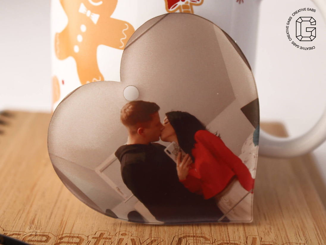 Herzförmige Acryl-Weihnachtskugel mit Foto – Größenvergleich neben weihnachtlicher Tasse